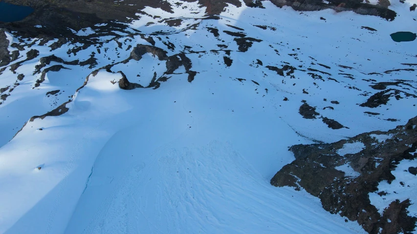 a snow covered mountain with a snowboarder coming down it