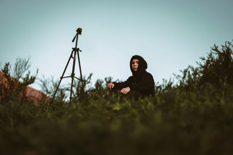 a person in a field sitting near a tower