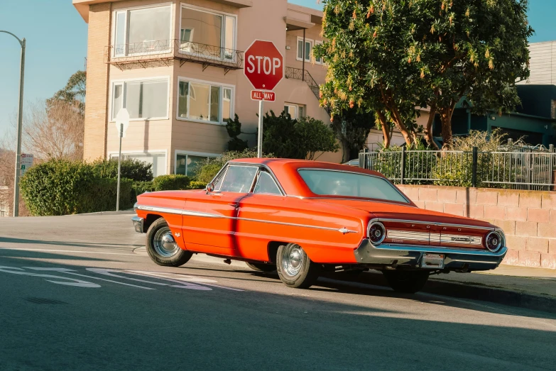 an orange vintage car parked on a city street