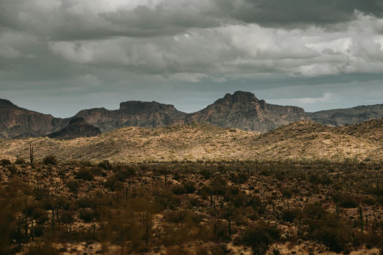 a couple of hills with a cloudy sky above them