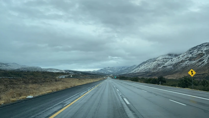 a deserted street leading to snow covered mountains