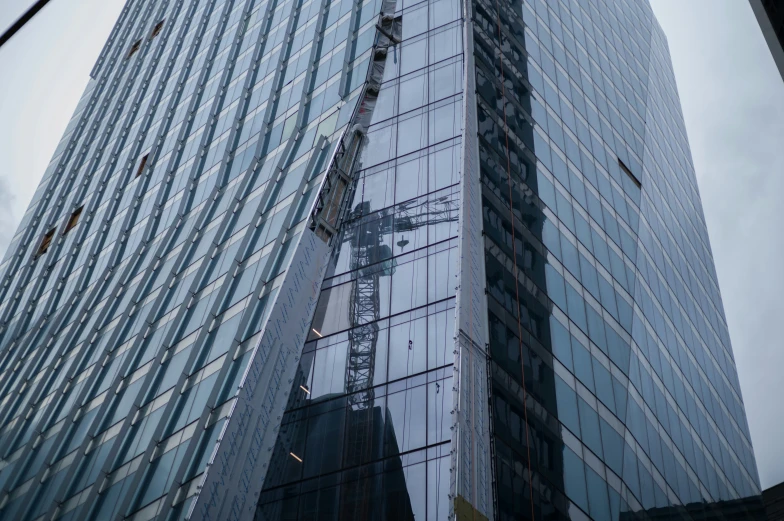 large building with cranes in the reflection of it