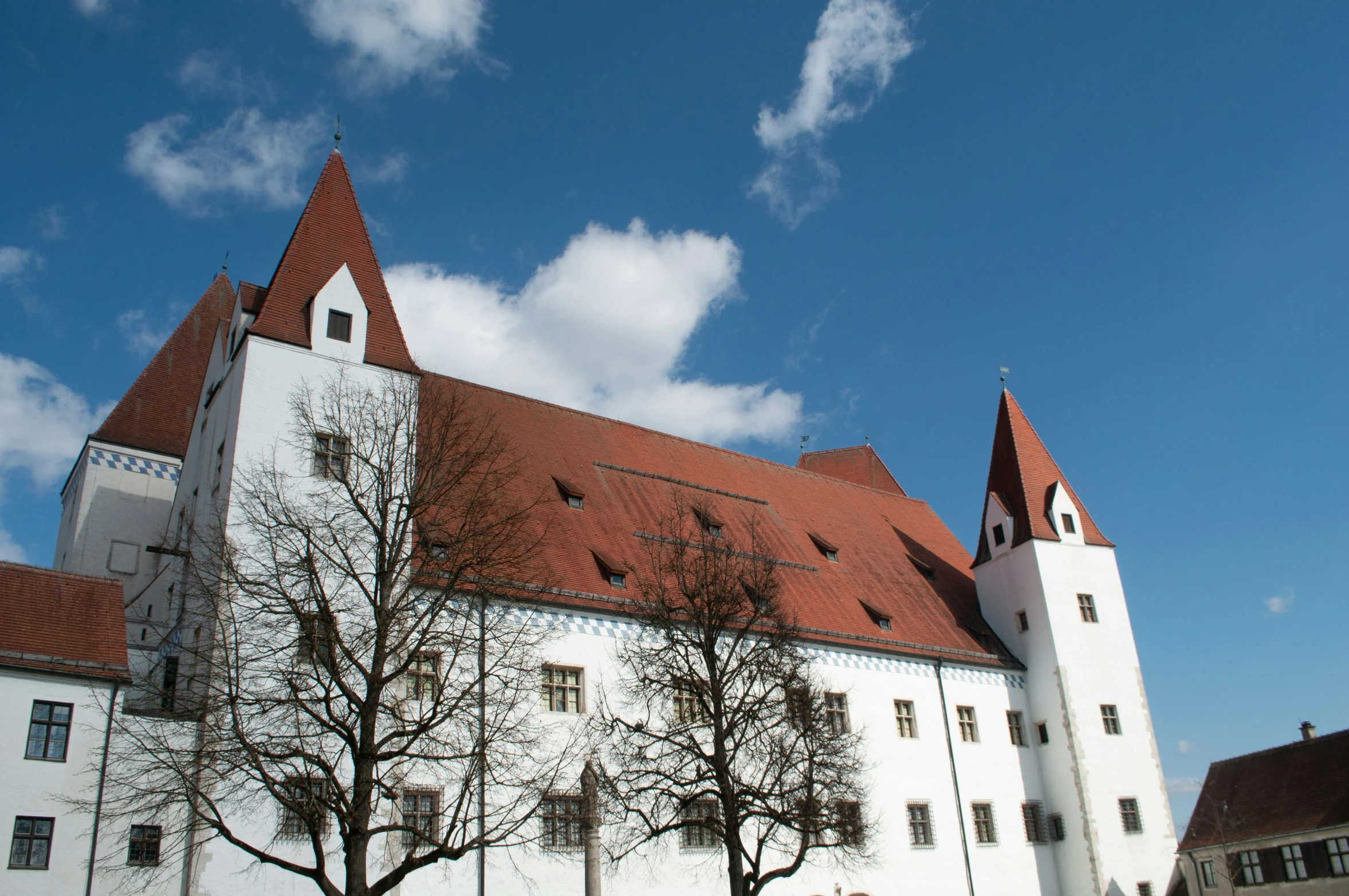 white building with brown roof under a blue sky with some clouds