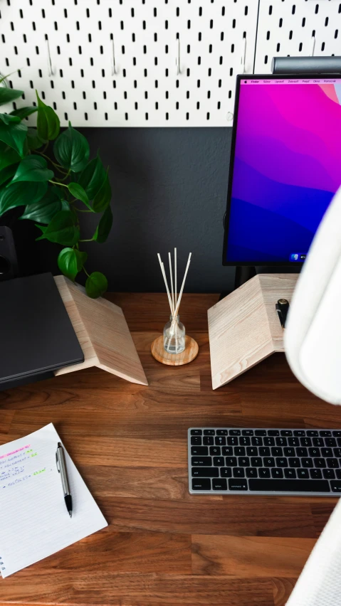 a desk has a desktop computer, a notebook and a keyboard on it