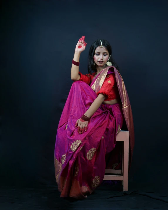 a woman in a sari is sitting on a chair