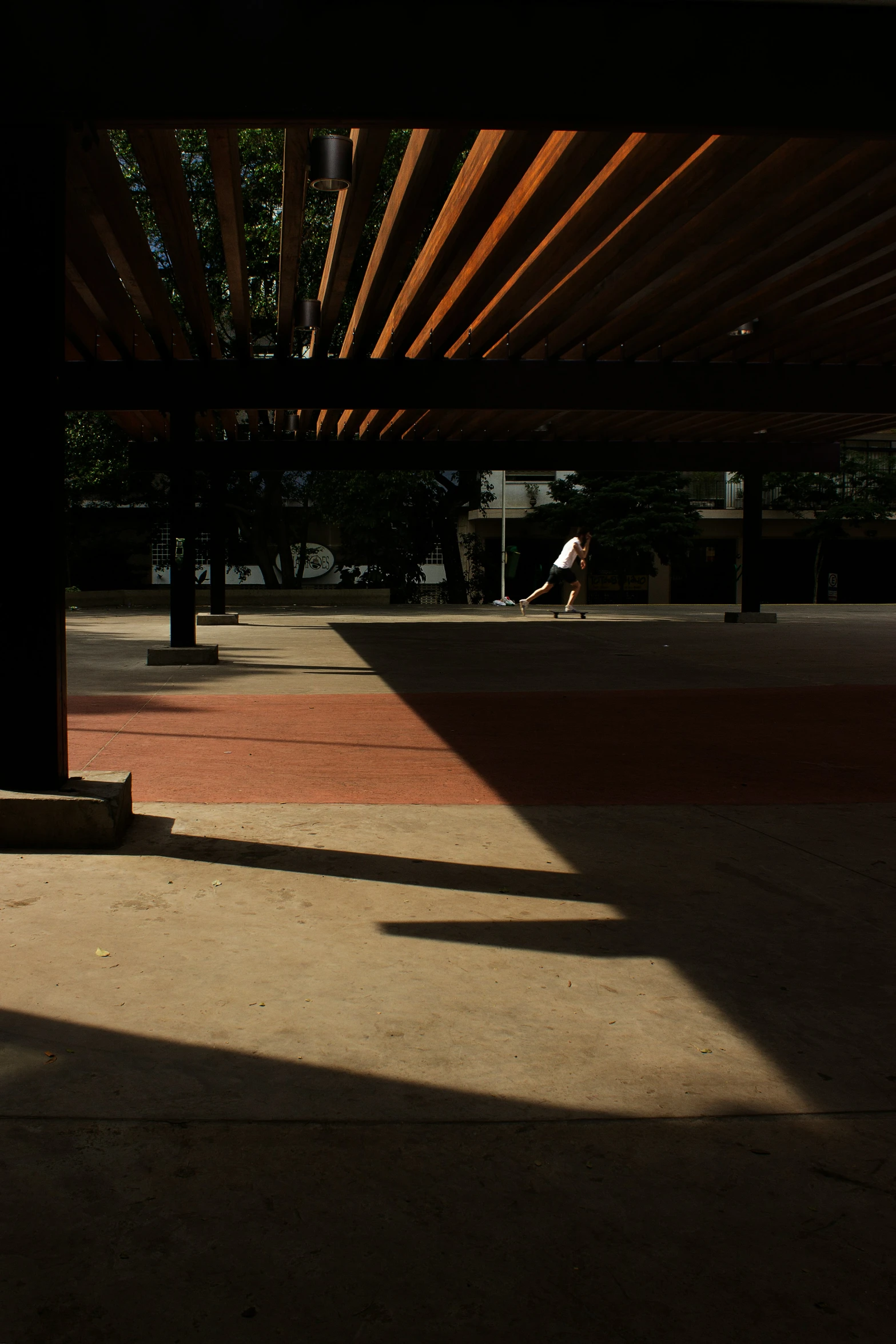 an empty sidewalk and a person standing in the distance with their foot up on a skateboard