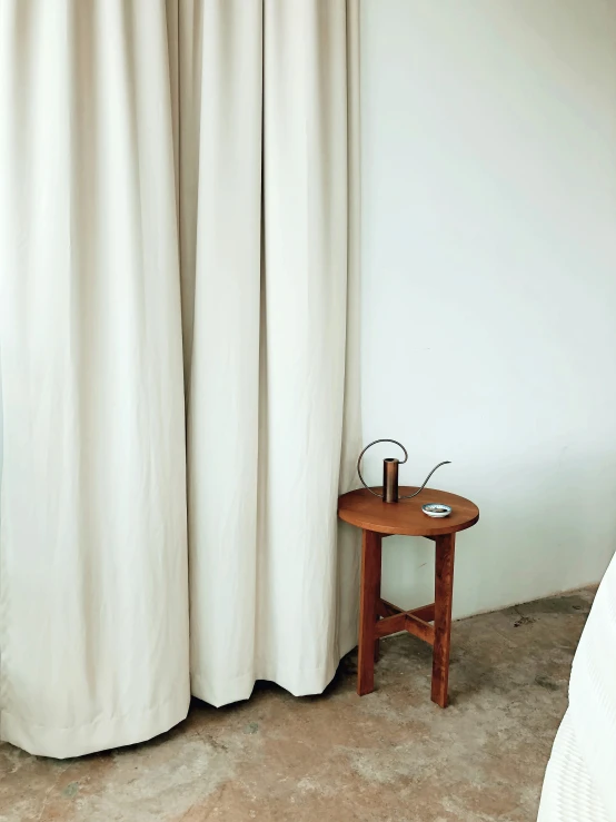 an unoccupied room with a wooden side table and white ds