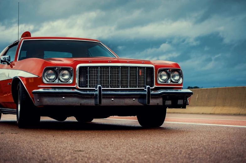 an old red classic car on the street under stormy skies