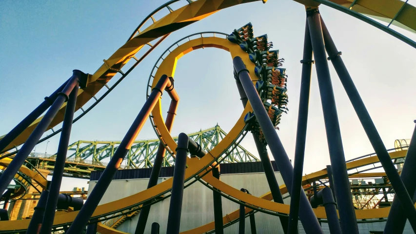 a yellow roller coaster going down the track at a theme park