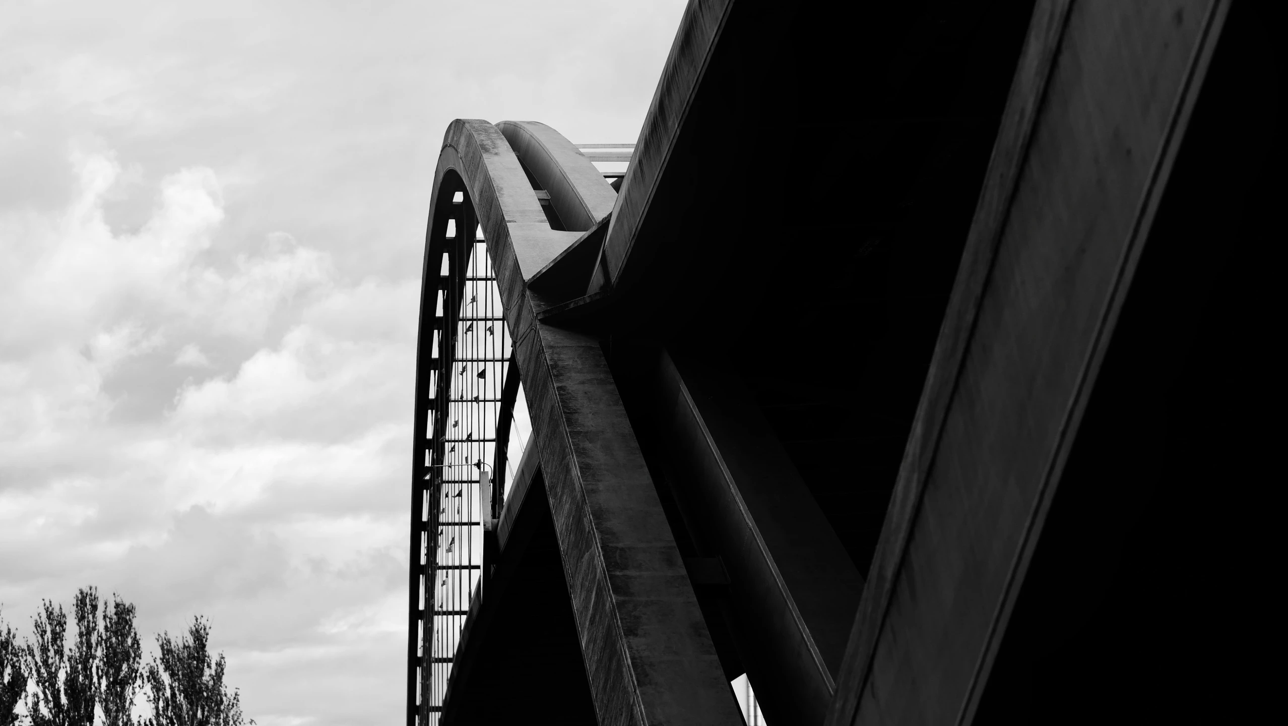 a train bridge next to some trees and a tall building