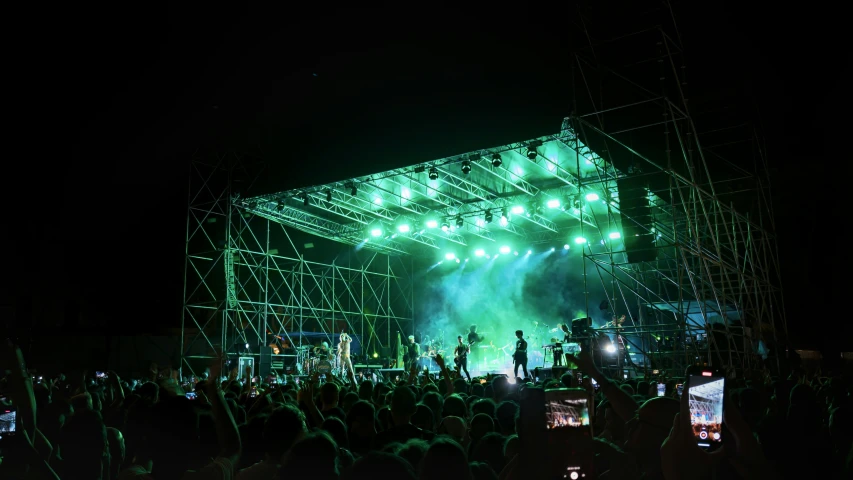 crowd gathered around with an illuminated stage in the background