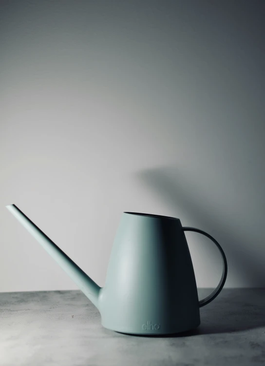 a blue watering can with a black handle on a table