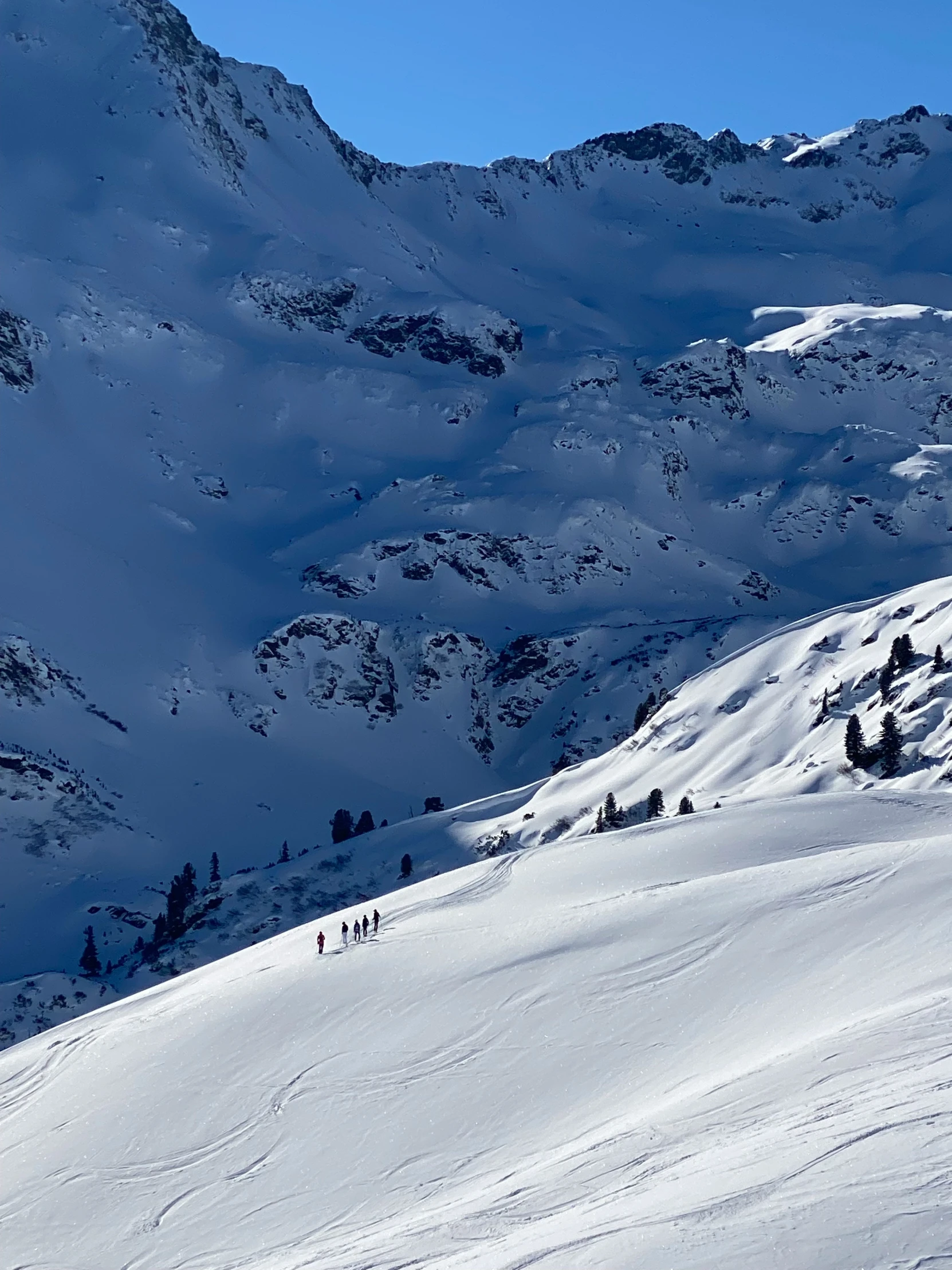 a very tall snowy hill with some people skiing on it