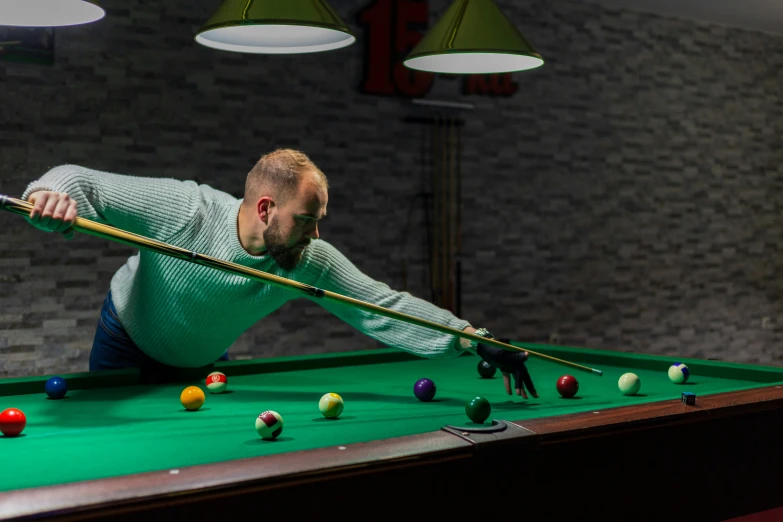 a man leaning over a pool table in front of many colorful balls