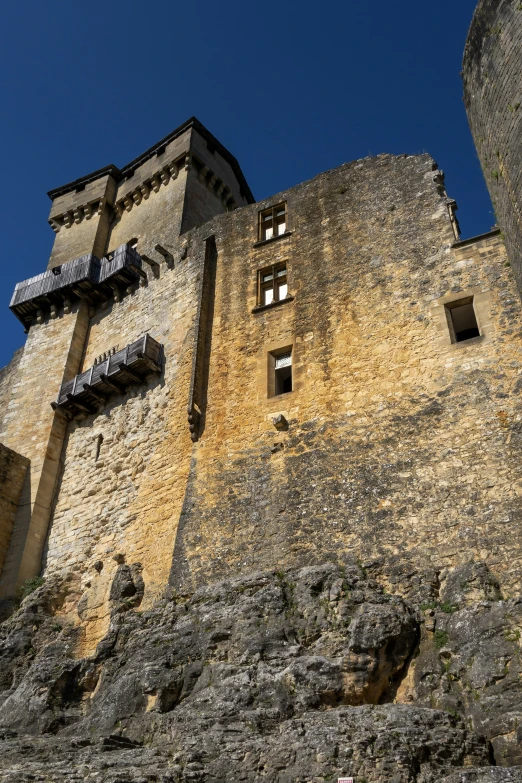 a brick castle with many windows sits atop the side of the hill