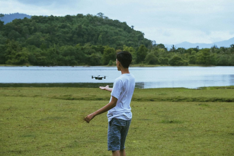 a young man playing frisbee in a field next to a lake