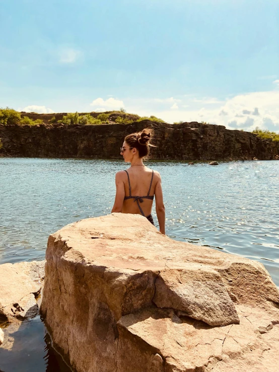the girl is sitting on a rock in the water