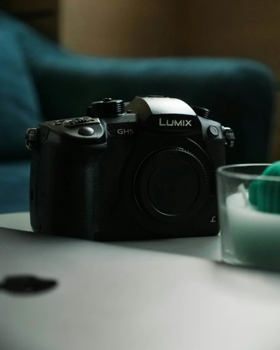 a camera is laying on a table next to a glass