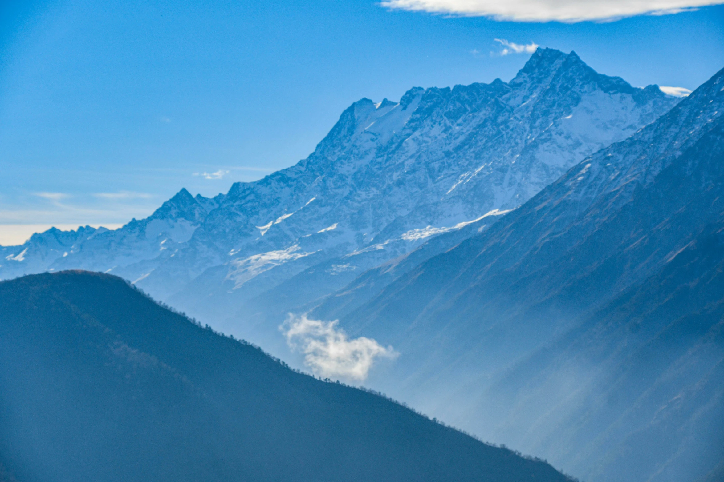 a snow covered mountain range under a blue sky