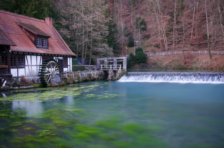 the water is very blue and the house near the waterfall