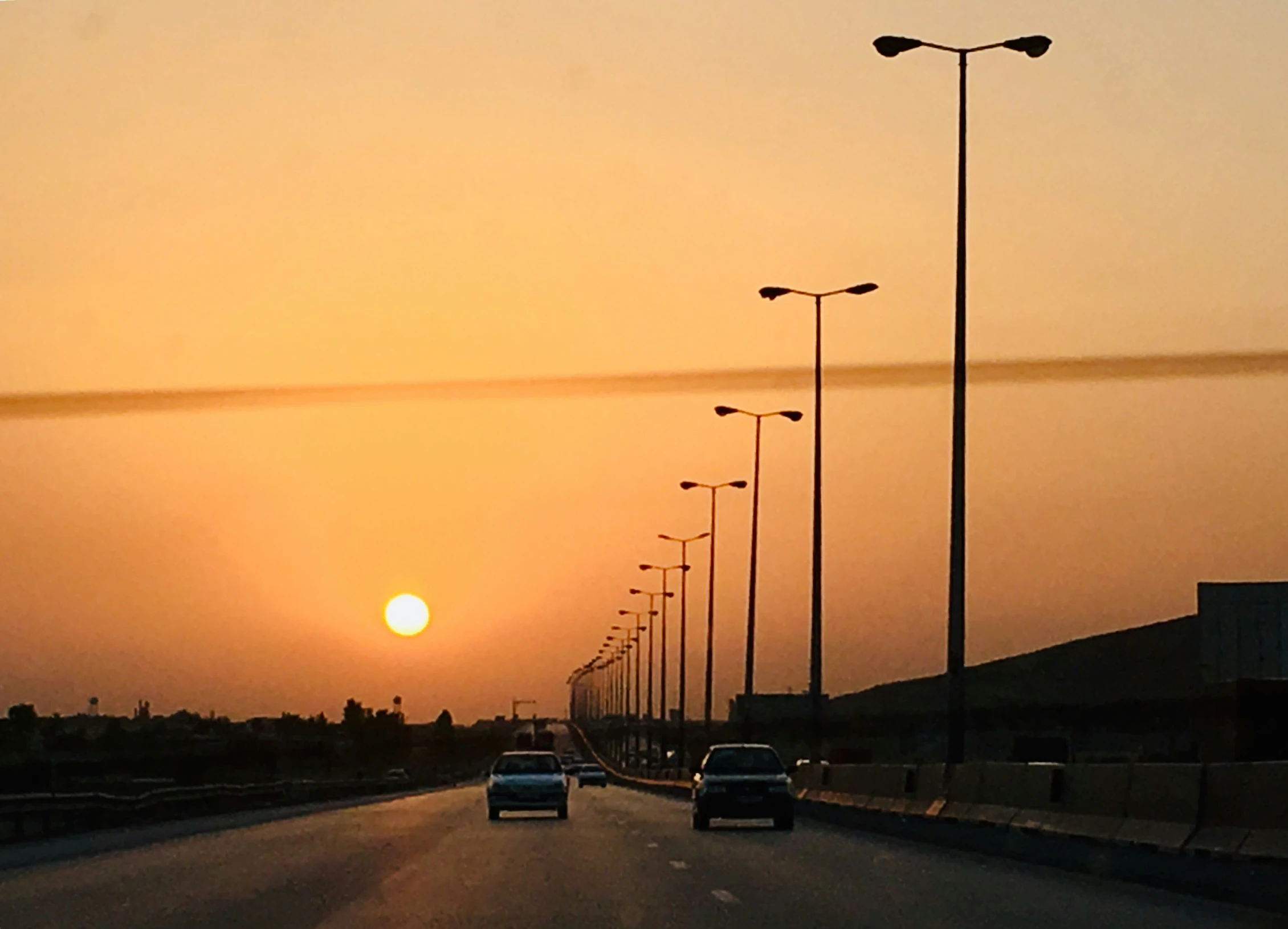 cars driving down an empty road during the sunset