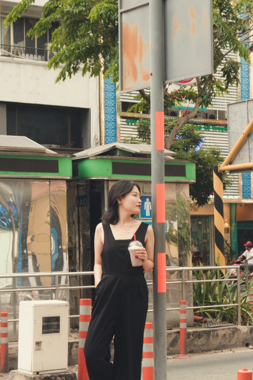 a woman standing on a sidewalk near a street sign