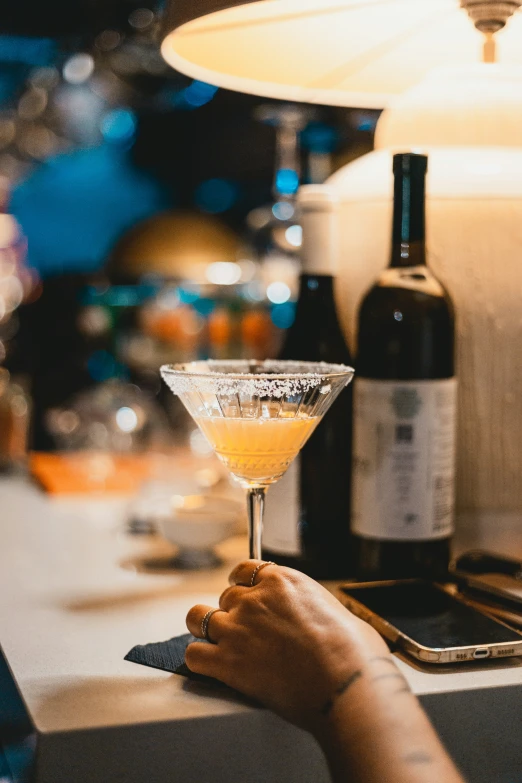 hand on counter holding up a glass with a liquid inside