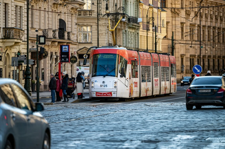 a trolley bus traveling down the street with some cars parked along it