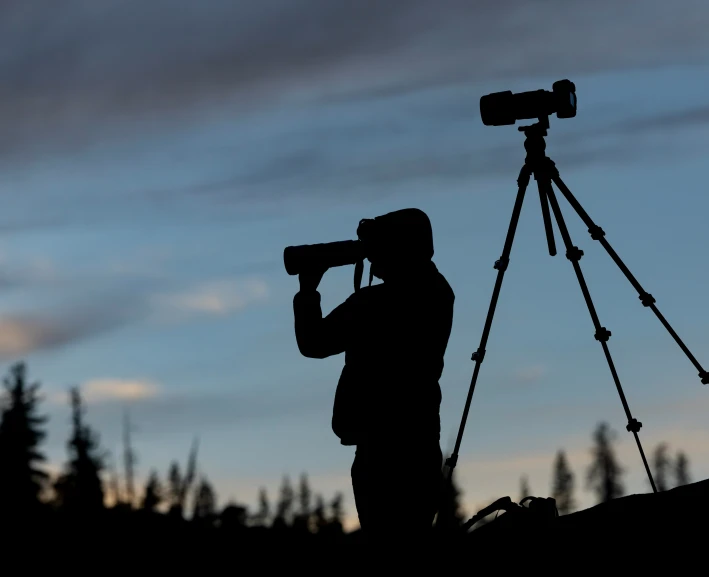 the silhouette of a pographer standing in front of a camera