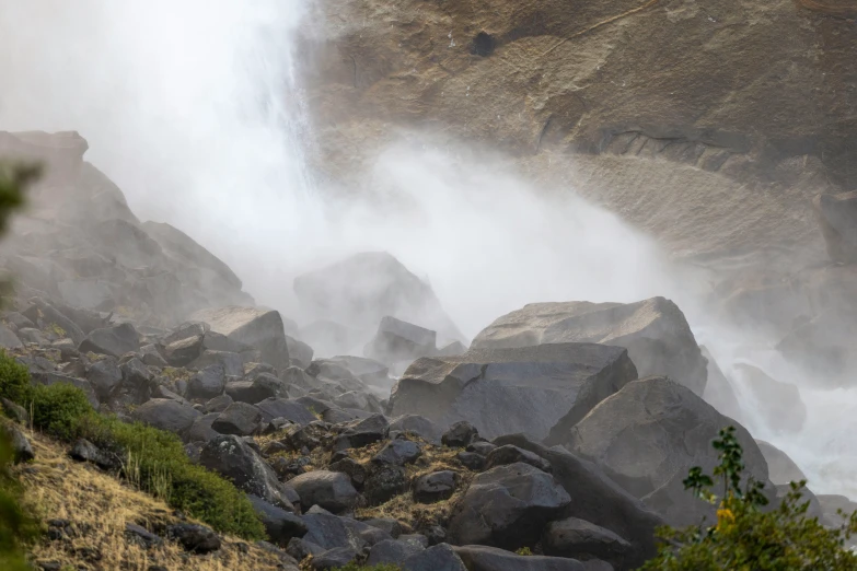 the water spraying is pouring down a rock cliff