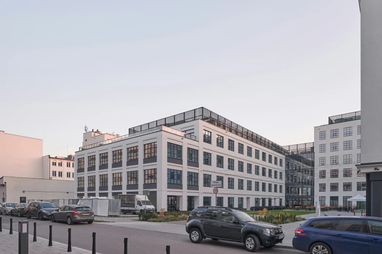 cars and trucks are parked on the road in front of a white building