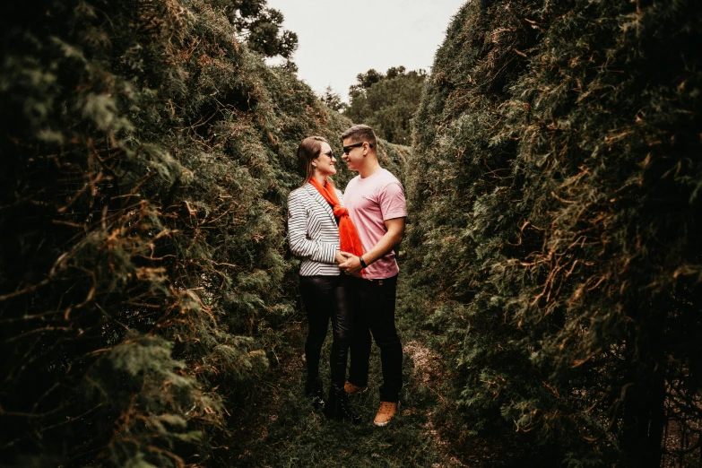 a couple stands in the tall green trees