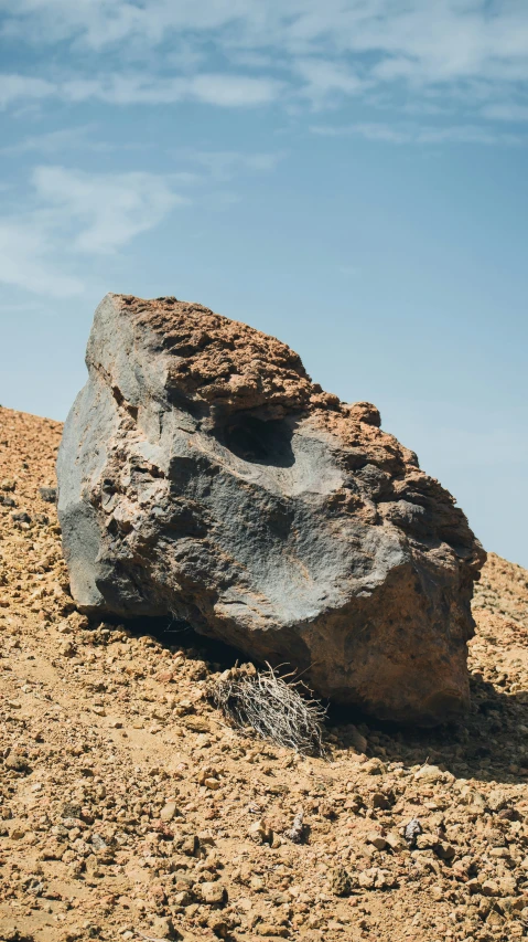 a large rock that is next to a grassy hill