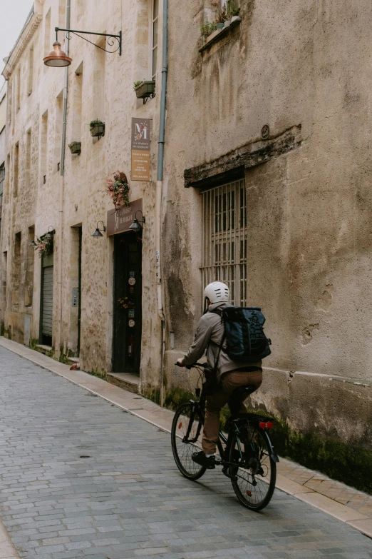 the person with a backpack rides his bike down the street