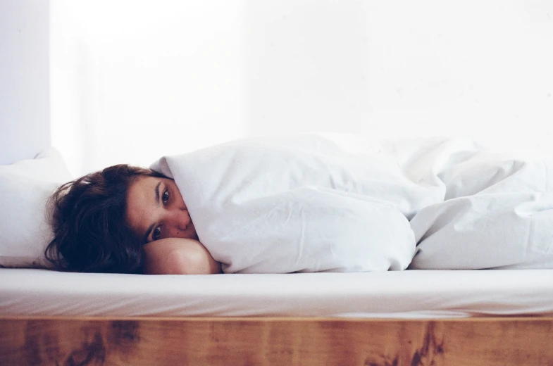 a woman laying on a white bed under pillows