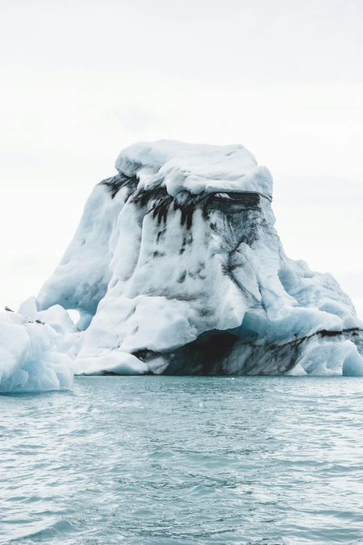 large iceberg floating across water next to land