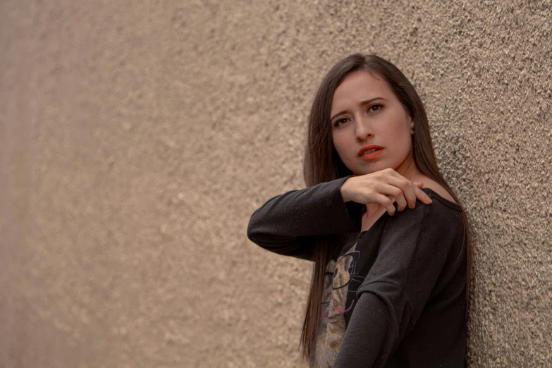 a woman is standing near a wall, with her hands on the hips