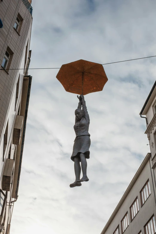 a statue hanging from a line holding an umbrella