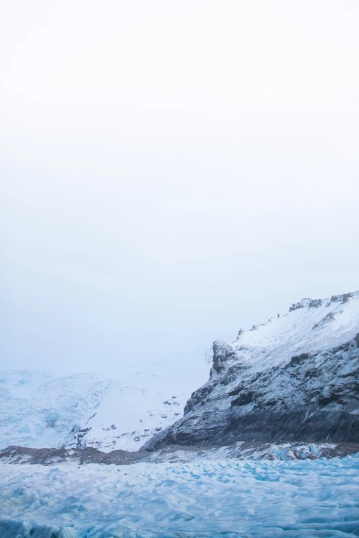 a snowy mountain overlooks water with small rocks