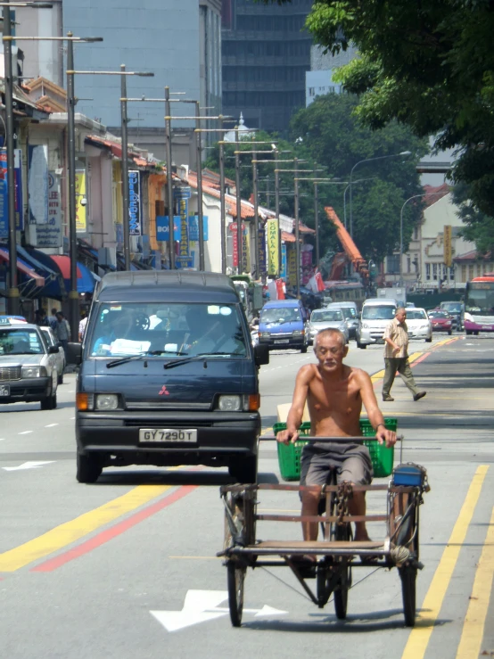 a man on a rickshaw pulling a small cart down a street