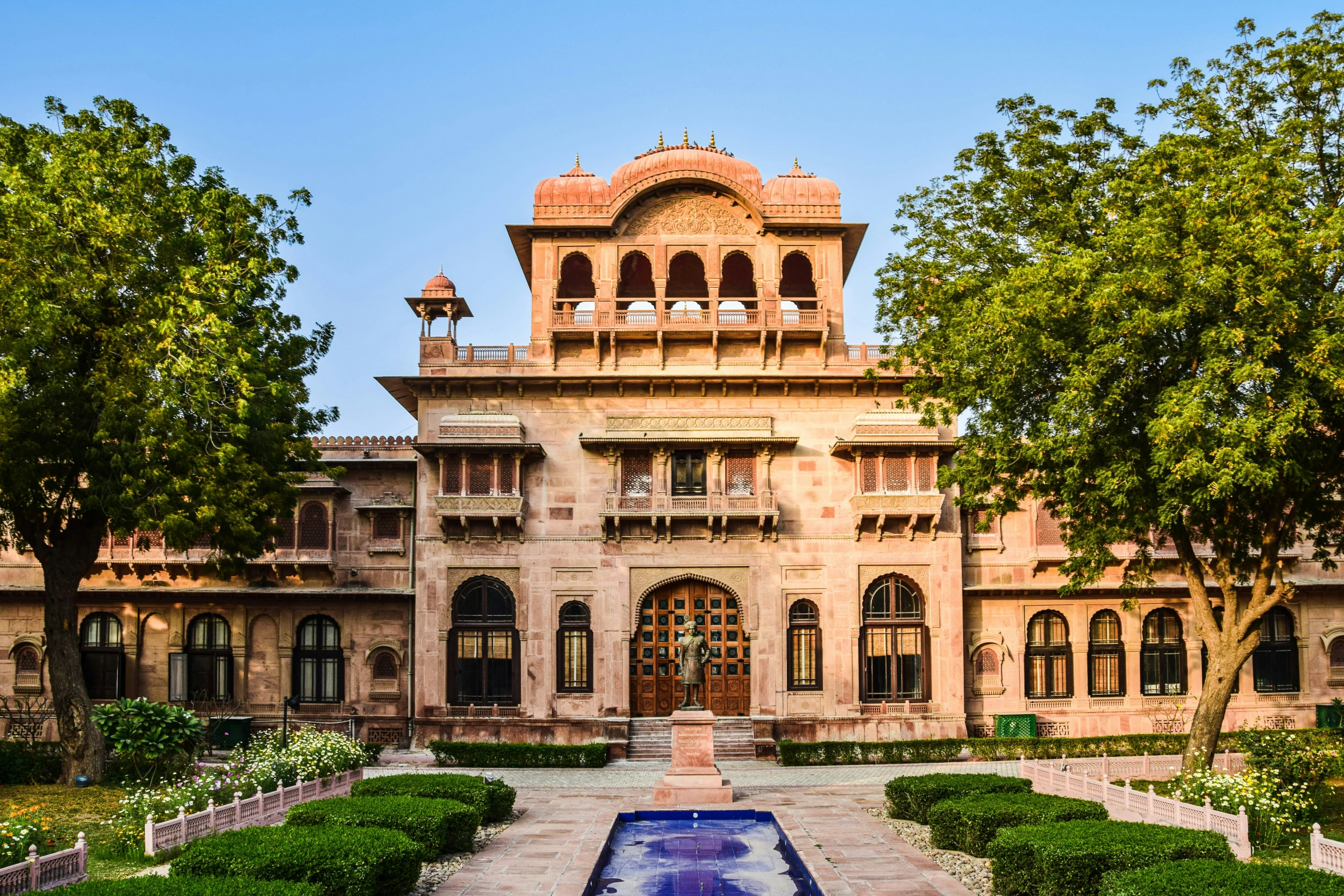 an elaborately designed mansion with a circular garden fountain