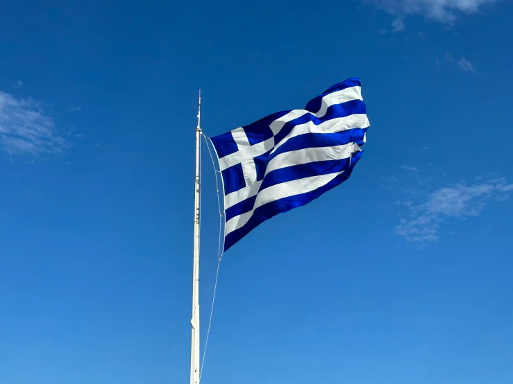 an greek and white flag waving from a pole