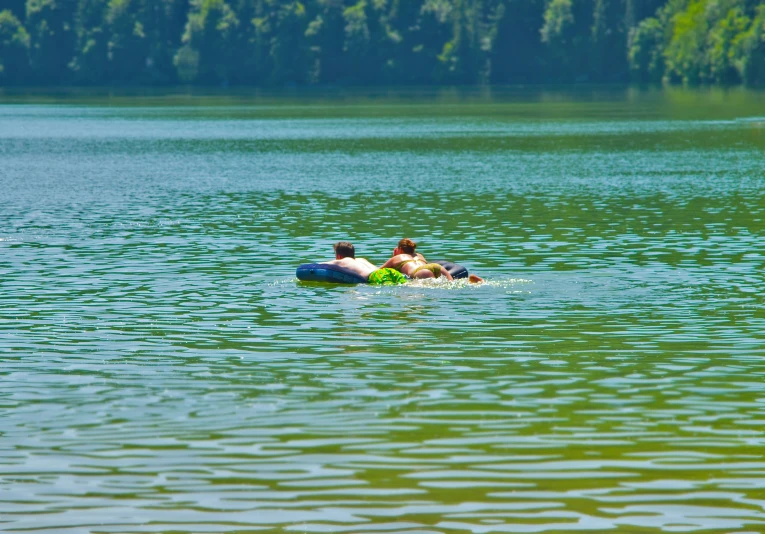 two people are swimming on an inflatable boat