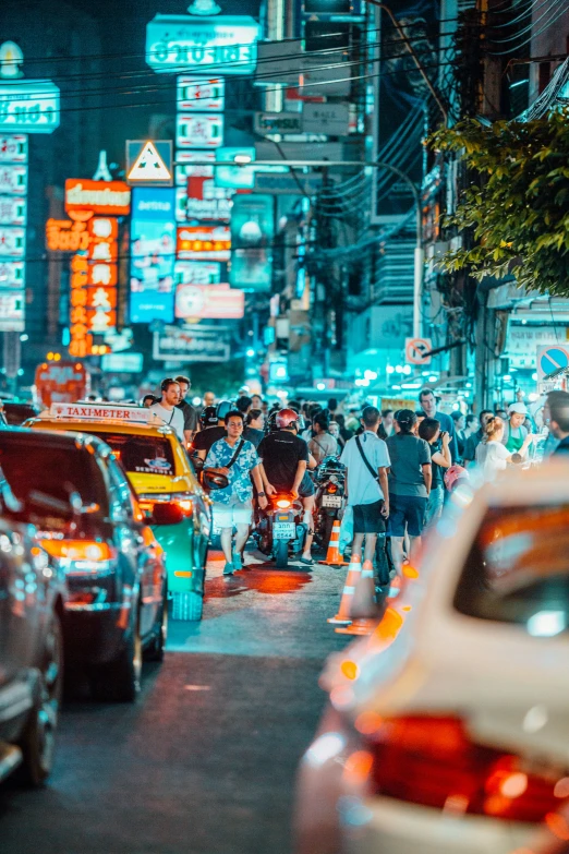 cars and people are going down a crowded street at night