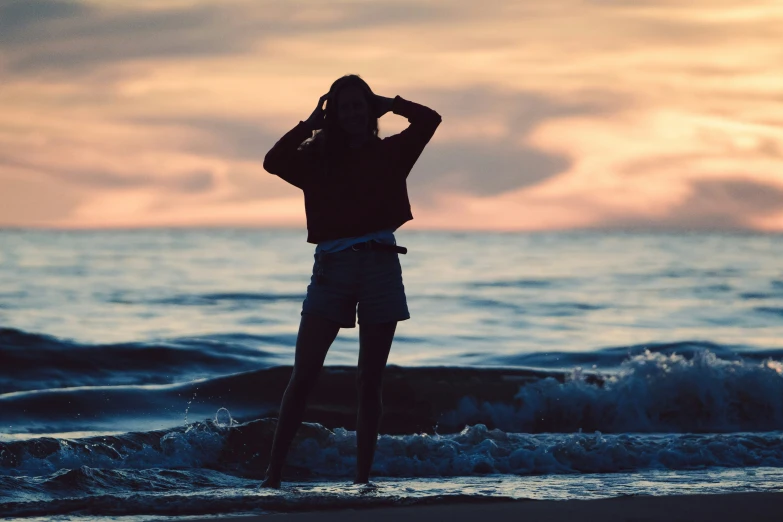 the silhouette of a man in swim trunks and hat standing on the beach