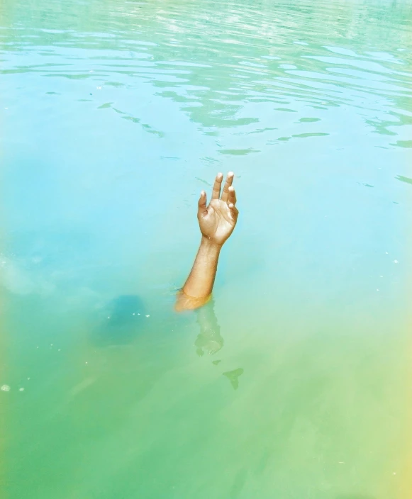 there is someone's hand in the water that is blue