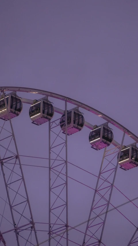 a ferris wheel lit up at night with purple skies