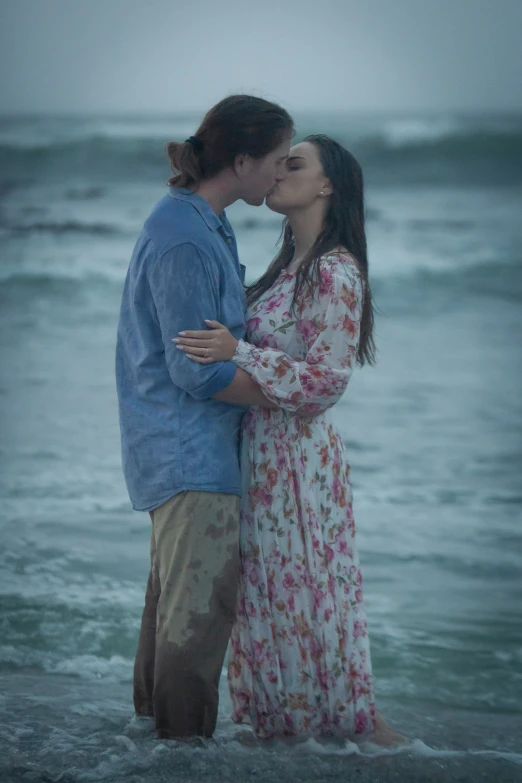 a man and a woman kissing on the beach in the rain