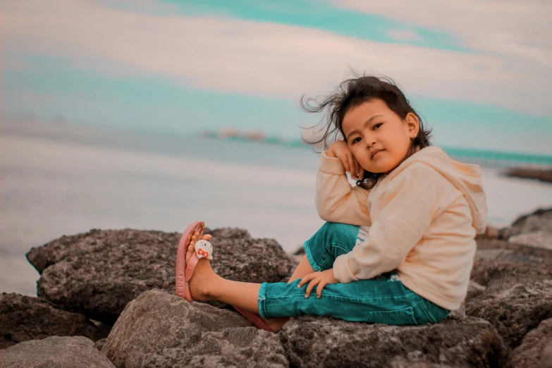 a little  sitting on some rocks and talking on a phone