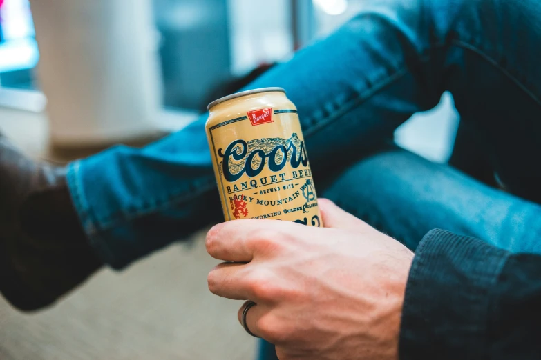 a can of beer sitting in someone's hand